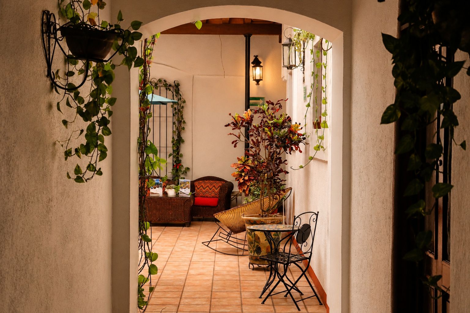 An indoor space with a tiled floor, a wicker chair, a small table, and hanging plants.