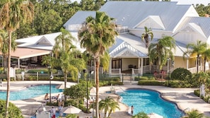 Ein Resort mit Swimmingpool, Palmen und einer überdachten Terrasse.