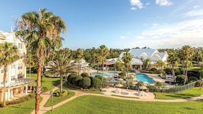 A resort with a swimming pool, palm trees, and a large building with a white facade. - 3BR Suite at WorldMark Kingstown Reef Near Disney & Universal Orlando (Orlando)