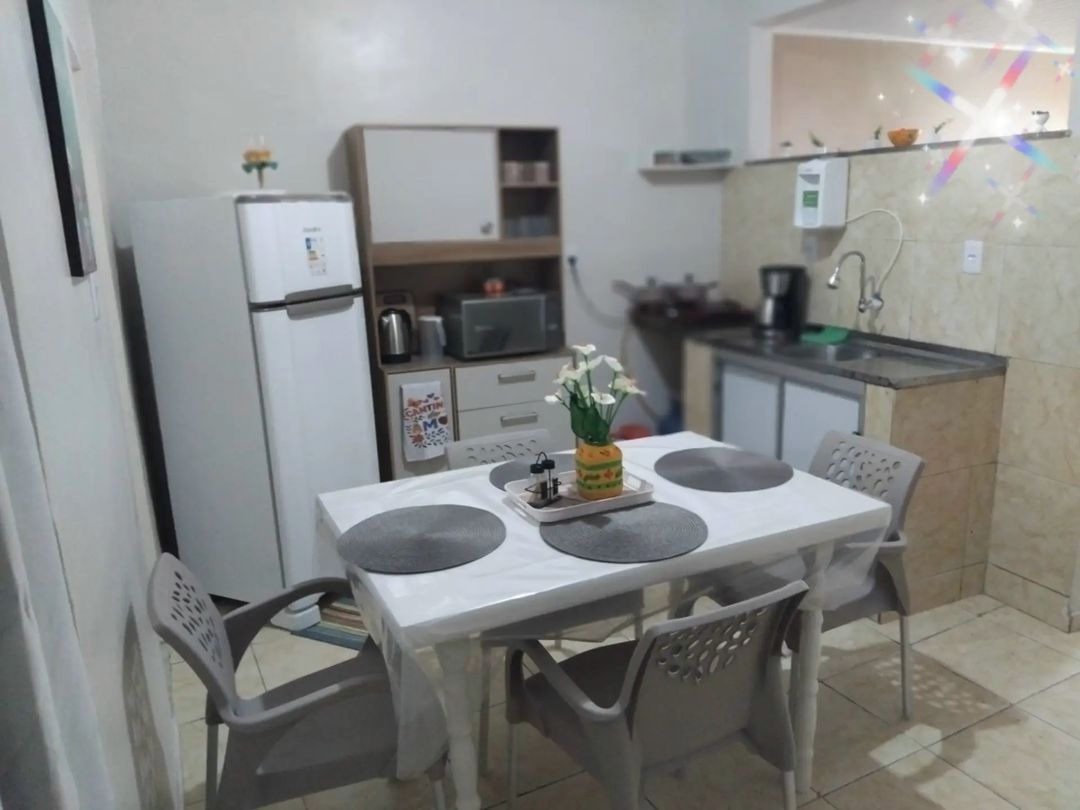 A compact kitchen with a dining table, chairs, a refrigerator, microwave, and a small cabinet.