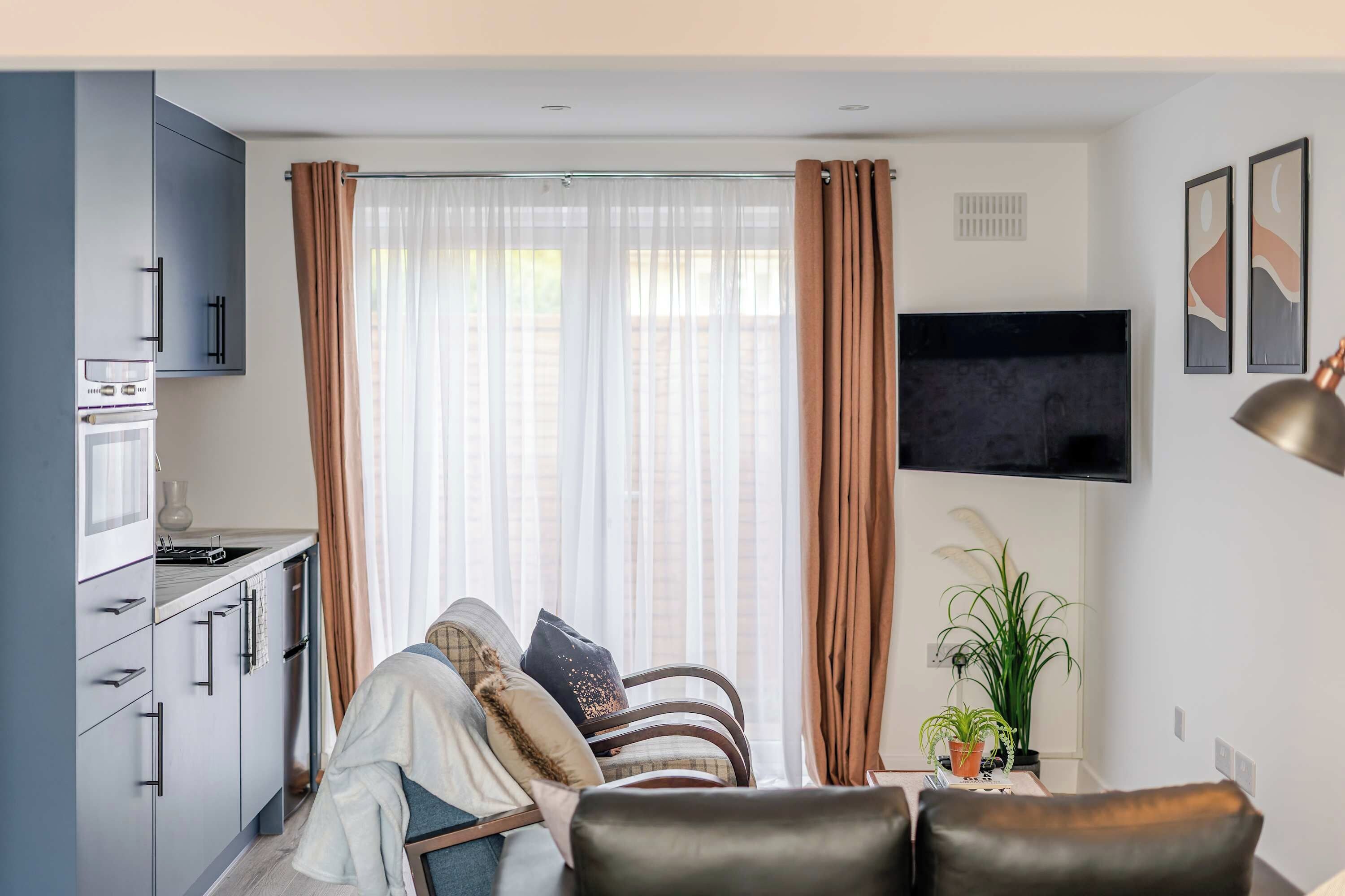A modern kitchen with a built-in oven and a dining area with a sofa and a coffee table.