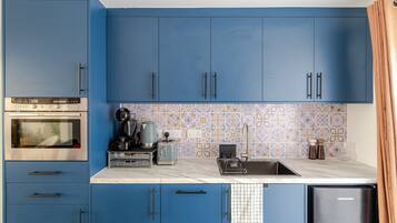 A modern kitchen with blue cabinets, a stainless steel oven, a coffee maker, and a toaster.