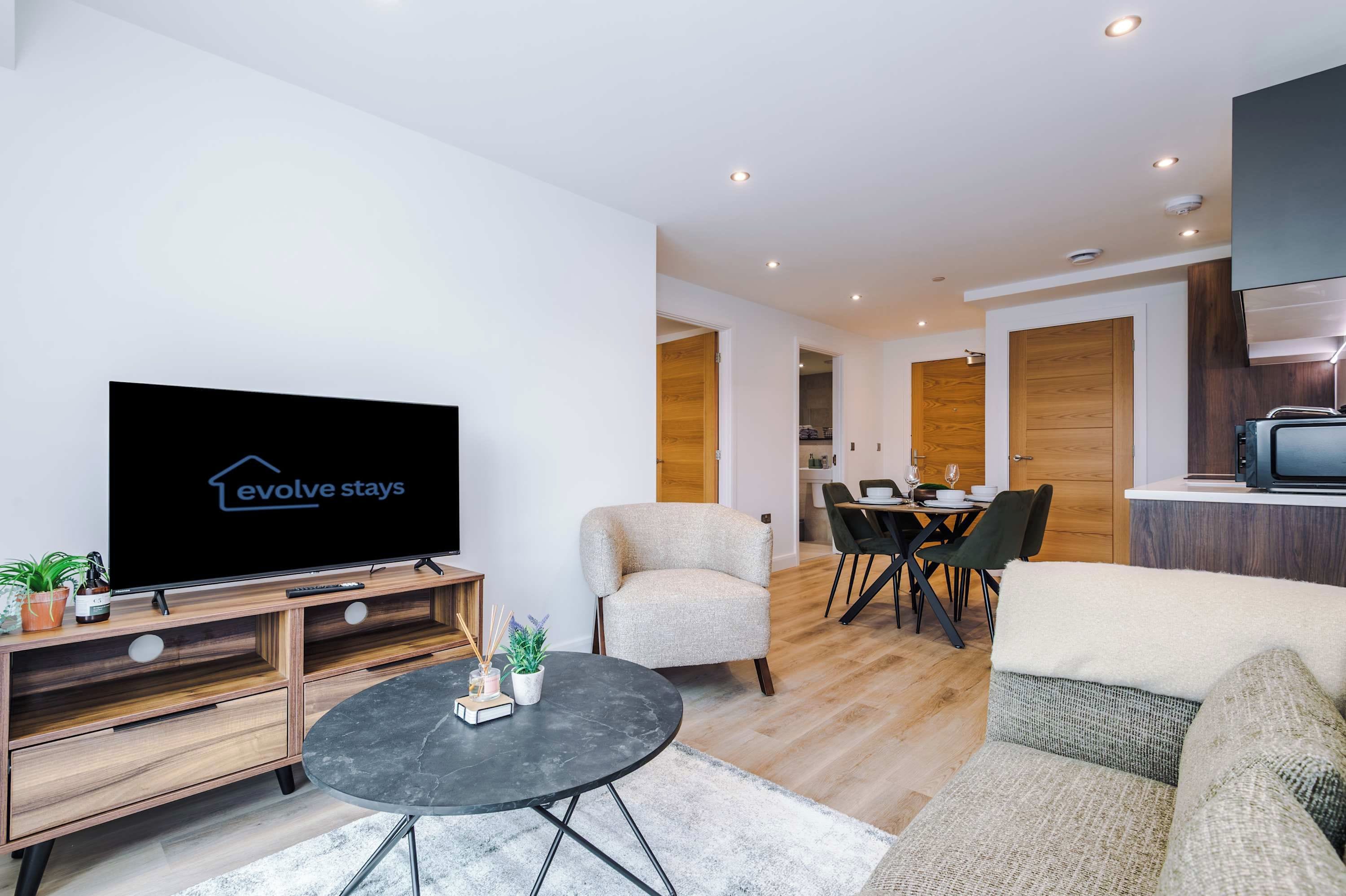 A modern living room with a flat-screen TV, a round coffee table, and a sofa.