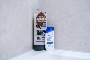 A shower area with a bottle of coconut & shea butter and a bottle of head & shoulders shampoo. - 1BR | Free Wi-Fi | Central Stay | Richmond Hill (Leeds)
