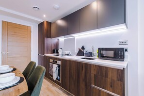 A modern kitchen with a built-in microwave, oven, and coffee maker. - 1BR | Free Wi-Fi | Central Stay | Richmond Hill (Leeds)