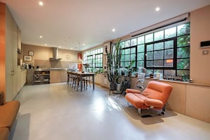 A modern kitchen with a dining area, large windows, and a seating area with a sofa. - The Hidden Mews House, by Veeve (London)