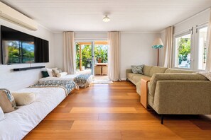 Un amplio espacio de estar con un sofá, una cama y un televisor montado en la pared.