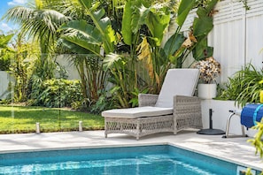 A poolside area with a wicker lounge chair, a small table, and a potted plant. - Solara Studio at Corlette (Corlette)