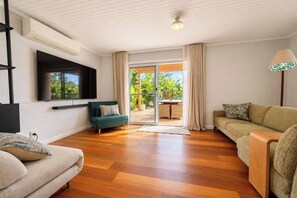 Una sala moderna con un sofá, un sillón verde y suelo de madera.