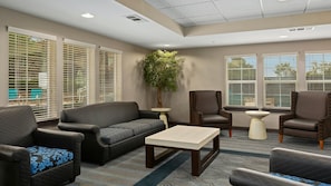 A hotel lobby with a sofa, armchairs, a coffee table, and a potted plant.