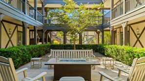 A courtyard with a central seating area, surrounded by greenery and a tree.
