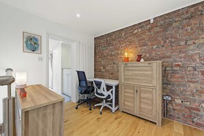 A modern office space with a brick wall, a desk, office chairs, and a cabinet. - Garden Duplex with 2 Baths - West Didsbury (Manchester)
