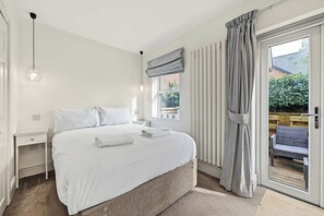 A bedroom with a bed, bedside tables, a window with curtains, and a view of the outside. - Garden Duplex with 2 Baths - West Didsbury (Manchester)