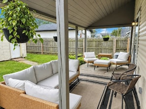 A covered patio area with wicker furniture, a hanging plant, and a view of the backyard. - Fountain Square 3BR Sleeps 6 Near Downtown (Indianapolis)