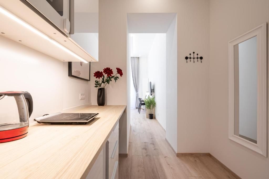 Eine moderne Küche mit Arbeitsplatte, einem Wasserkocher und einer Vase mit Blumen.