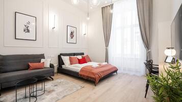 Ein modernes Schlafzimmer mit Bett, Sofa, Schreibtisch und Stuhl.