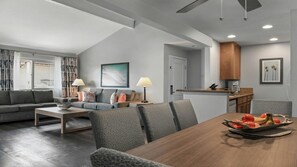 Una sala moderna con sofá, mesa de centro y comedor con mesa lista para una comida.