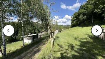 Ländliche Landschaft mit einem Feldweg, Holzzaun und einem kleinen Gebäude.