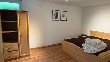 A bedroom with a wooden bed, a wardrobe, and two framed pictures on the wall.