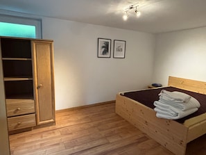 A bedroom with a wooden bed, a wardrobe, and two framed pictures on the wall. - Apartment 'Klein' with Shared Terrace and Shared Garden (Waldkirchen)