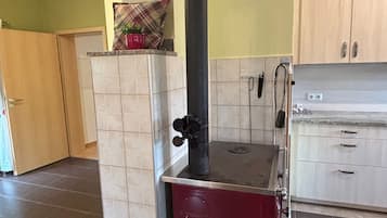 Une cuisine équipée d’une cuisinière intégrée, d’une hotte noire et d’un meuble rouge.