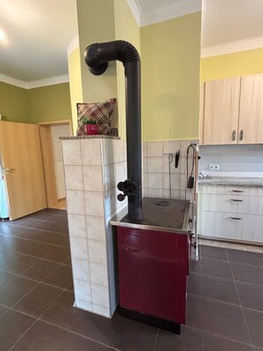 A kitchen with a built-in stove, a black exhaust pipe, and a red cabinet. - Apartment 'Groß' with Shared Terrace, Shared Garden and Balcony (Waldkirchen)