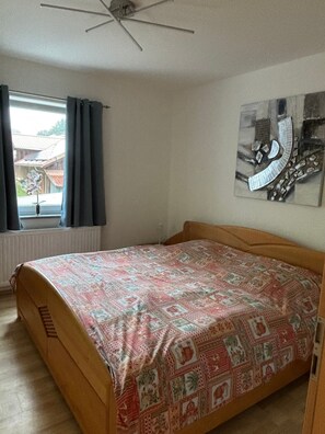 A bedroom with a bed, a ceiling fan, a window with curtains, and a wall-mounted artwork. - Apartment 'Groß' with Shared Terrace, Shared Garden and Balcony (Waldkirchen)
