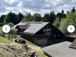 A building with a sloped roof, solar panels, and a garage. - Apartment 'Groß' with Shared Terrace, Shared Garden and Balcony (Waldkirchen)