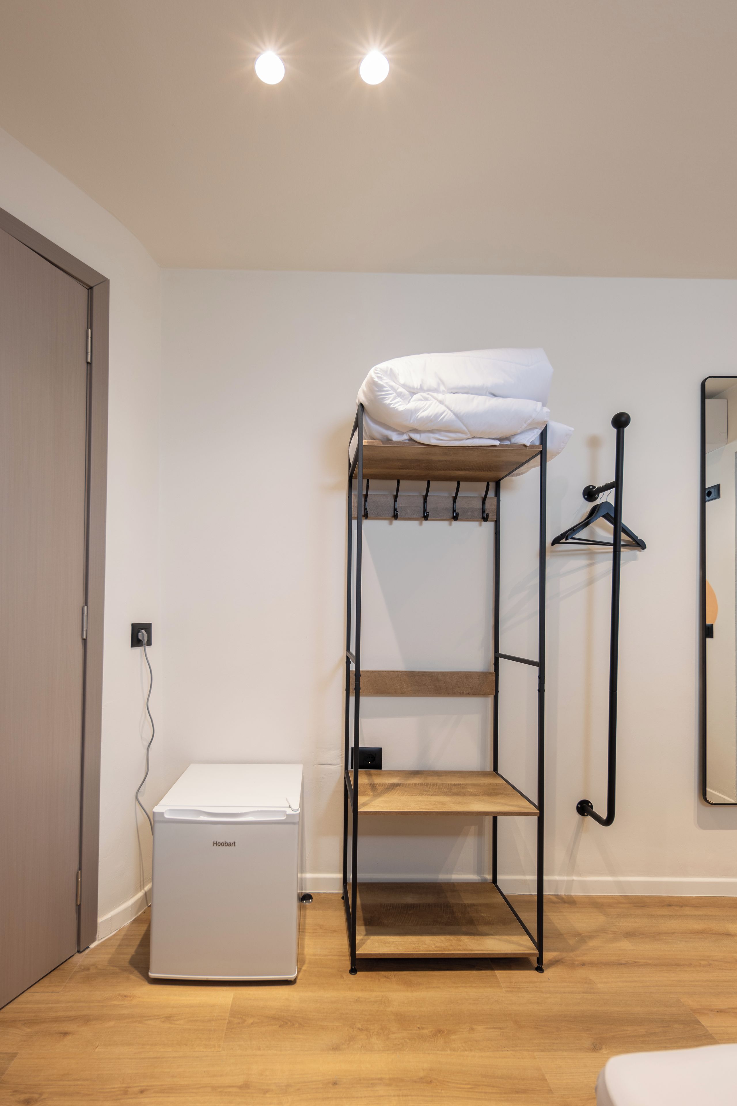 Una cama litera con estructura de madera, colchón blanco y un pequeño electrodoméstico debajo.