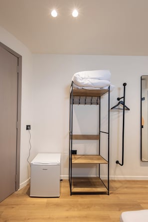 Una cama litera con estructura de madera, colchón blanco y un pequeño electrodoméstico debajo.