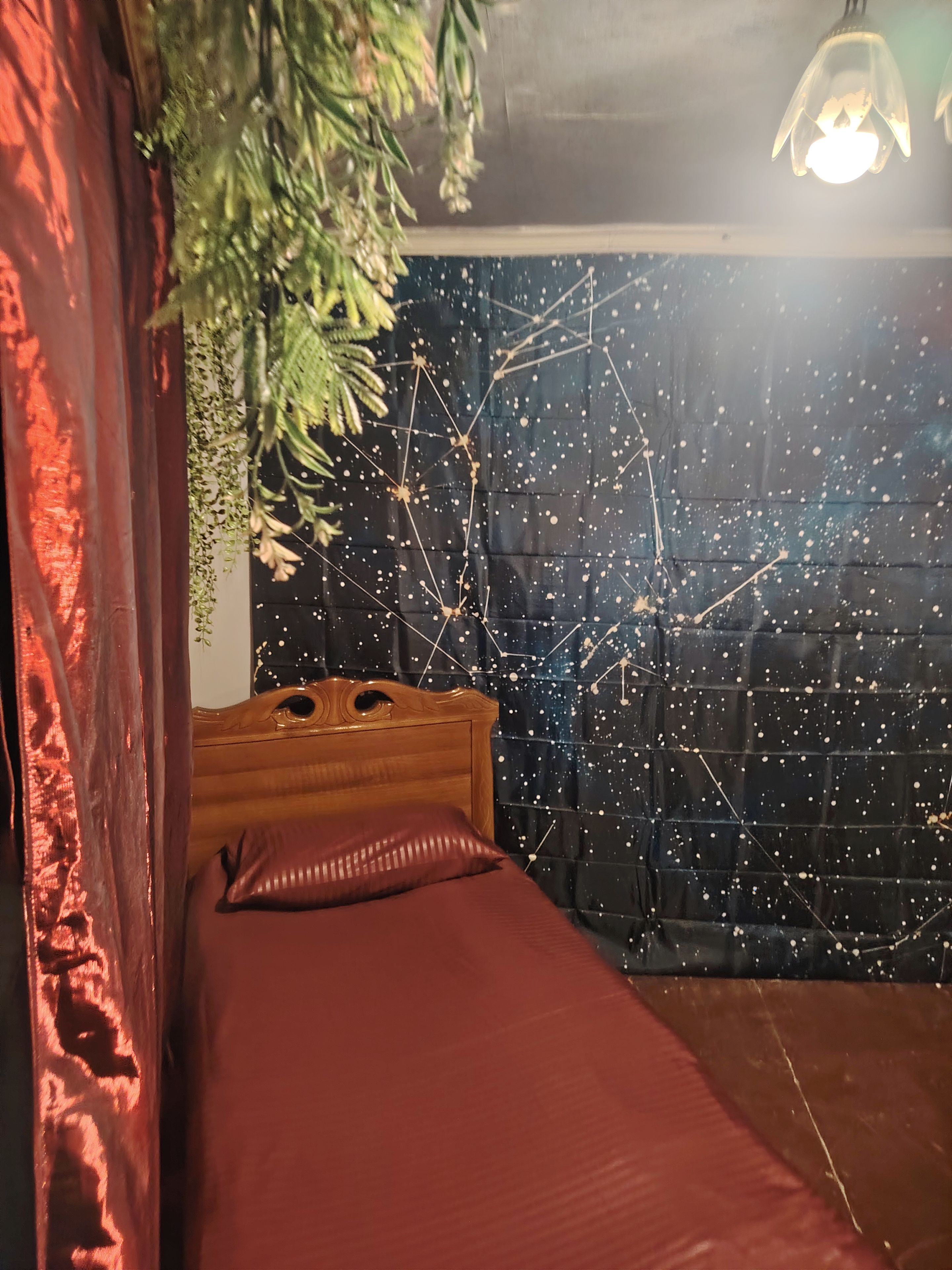 Una stanza con un letto, una testiera in legno, una coperta rossa e una parete decorata con un motivo a stelle.
