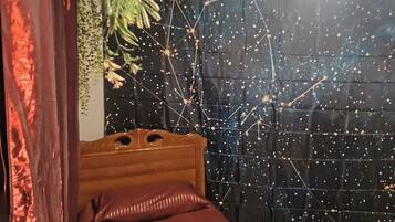 Una stanza con un letto, una testiera in legno, una coperta rossa e una parete decorata con un motivo a stelle.