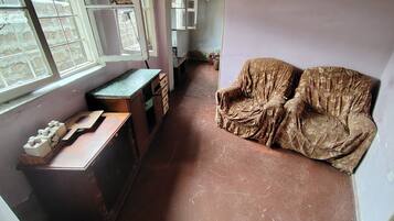 Ein Zimmer mit Schreibtisch, zwei Stühlen, einem Fenster und einer Tür zu einem anderen Raum.