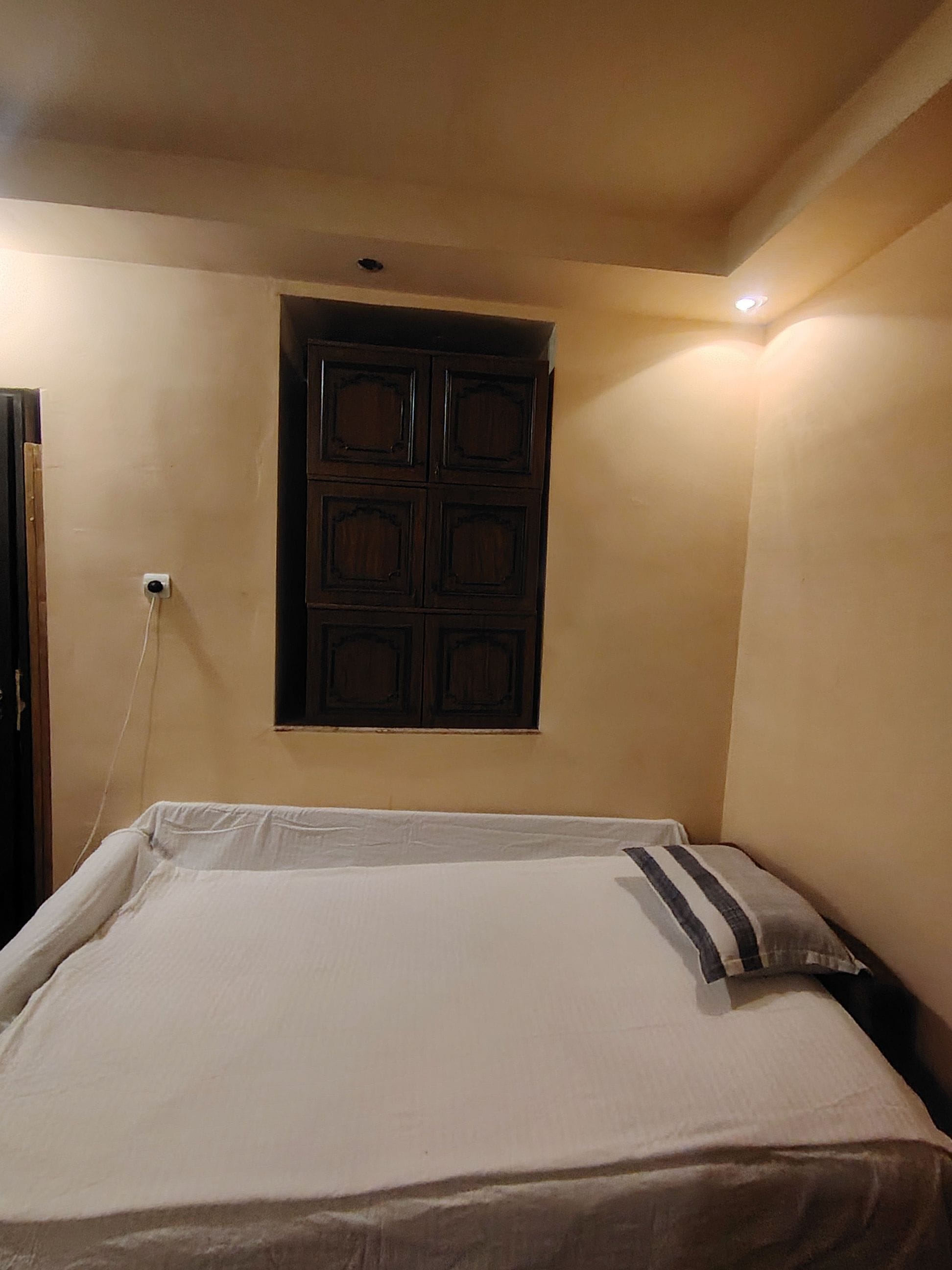 A room with a bed, a wall-mounted cabinet, and a ceiling light.