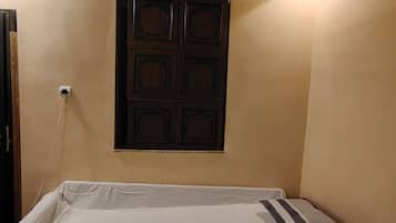 A room with a bed, a wall-mounted cabinet, and a ceiling light.