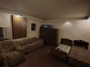 A room with a sofa, a bed, a cabinet, and a television.