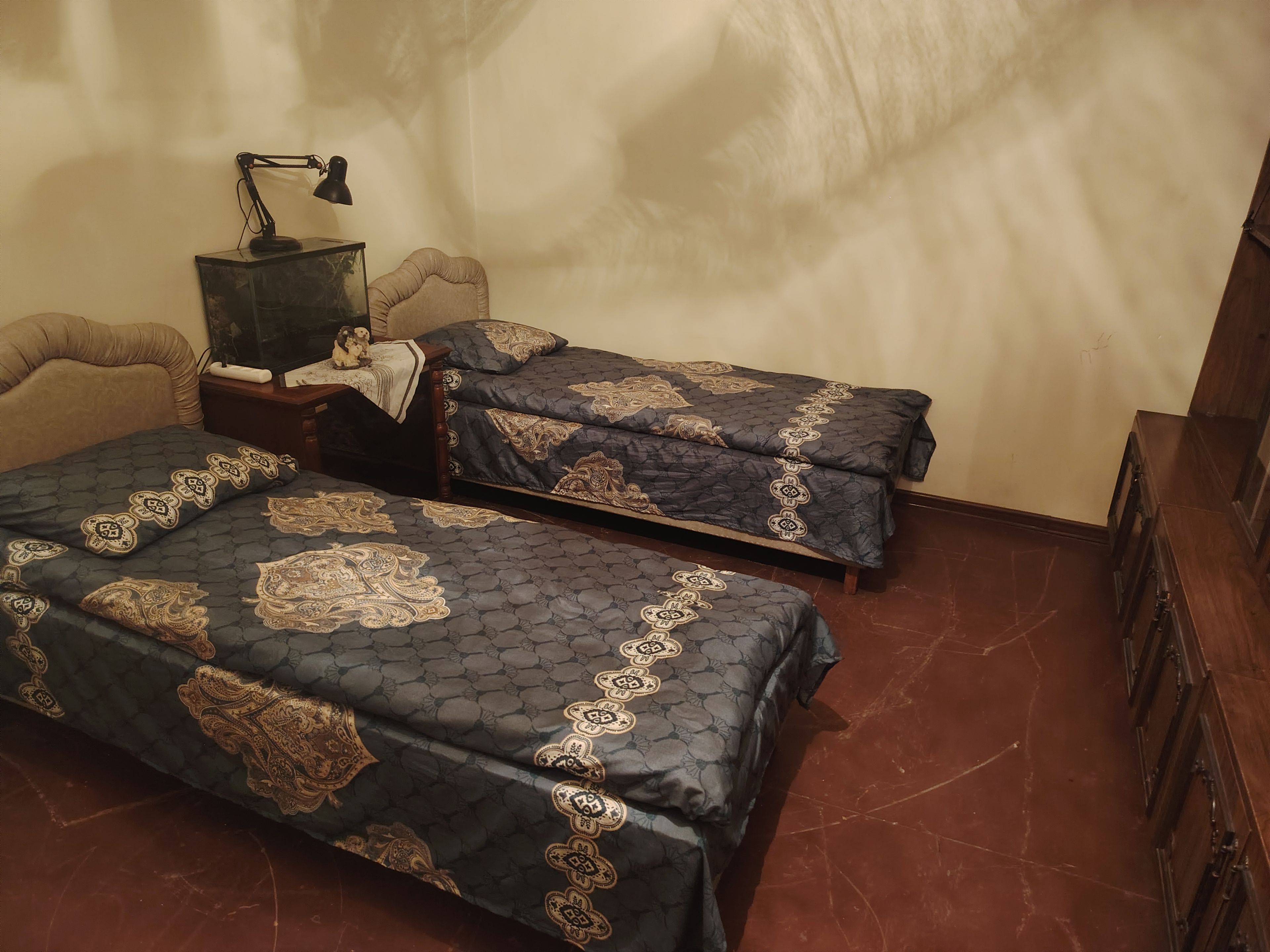 Une chambre avec deux lits, un bureau, une lampe et une chaise.