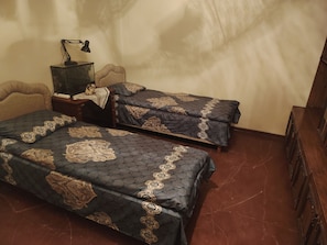 A room with two beds, a desk, a lamp, and a chair.