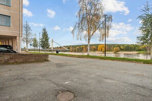 Parkkipaikka, jonka taustalla on silta, joki ja syksyisessä loistossaan kukkivat puut.