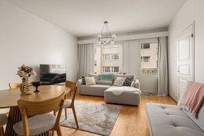 A modern living room with a sofa, ottoman, dining table, chairs, and a TV. - Arctic Riverside Retreat – Private Sauna - Central (Rovaniemi)