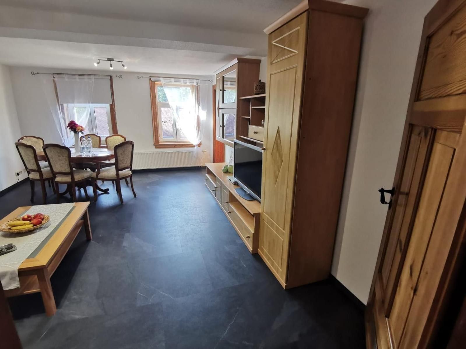 Une pièce comprenant une table à manger, des chaises, un téléviseur et une armoire.
