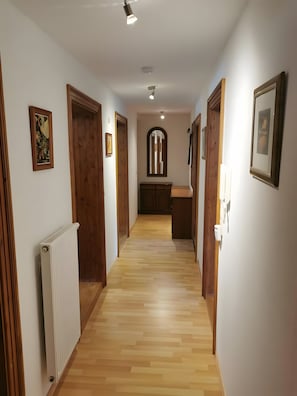 Un passadís amb portes de fusta, un radiador i quadres amb marc a les parets.