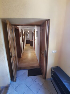 A hallway with wooden doors, a tiled floor, and a bench.