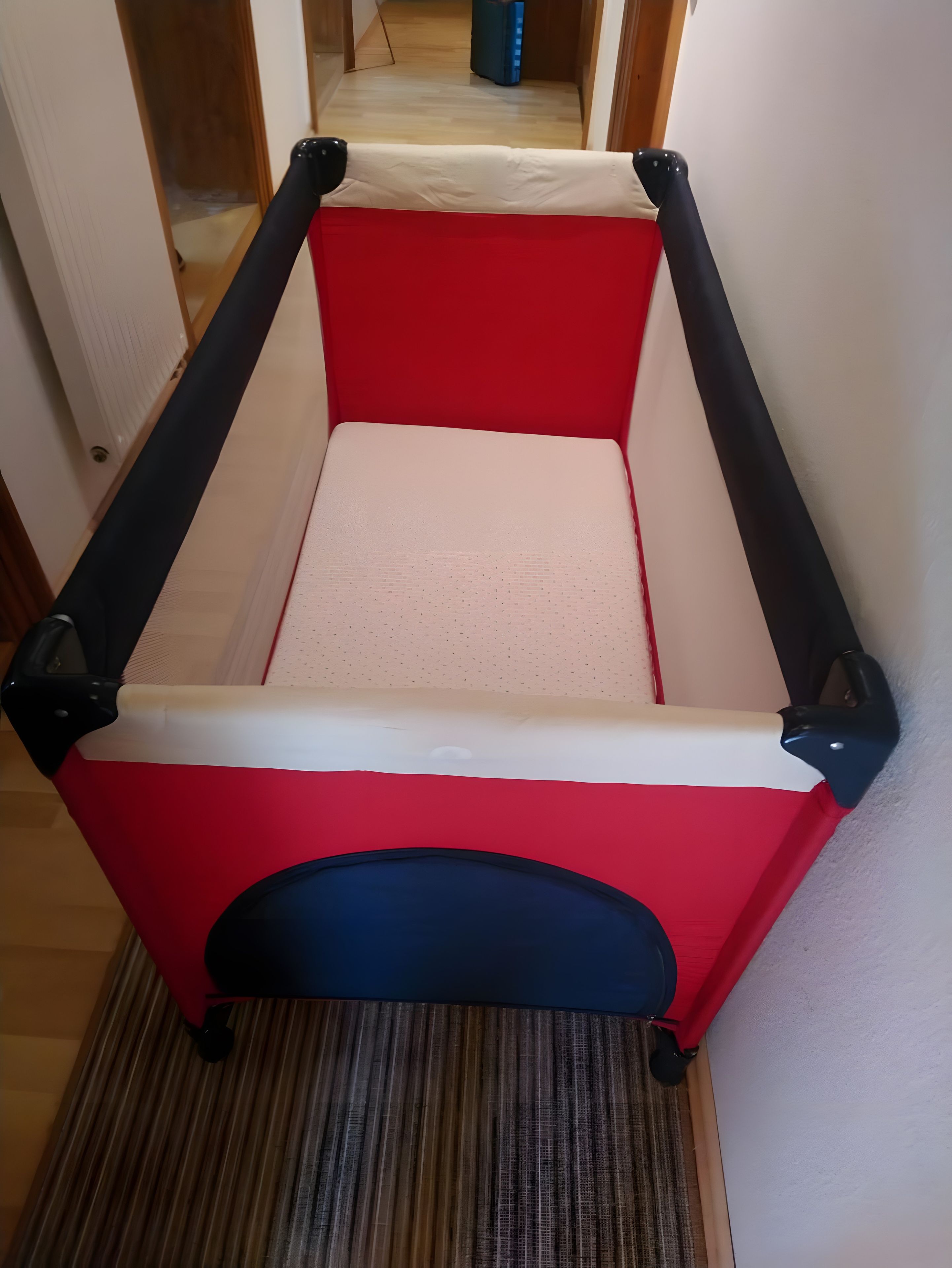 Una mesa de billar con diseño rojo y blanco, ubicada en una habitación con suelo de madera y una puerta al fondo.