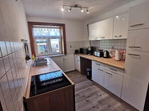A kitchen with a window, white cabinets, a stove, and various appliances.