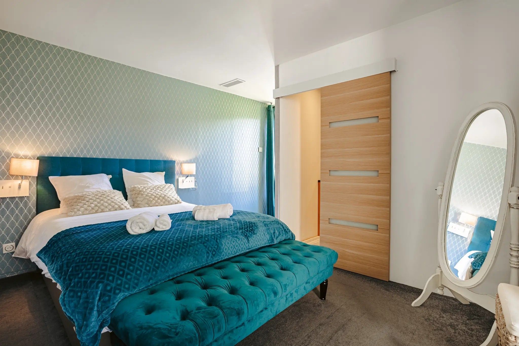 Une chambre à coucher avec un lit, un banc, un miroir et une armoire.
