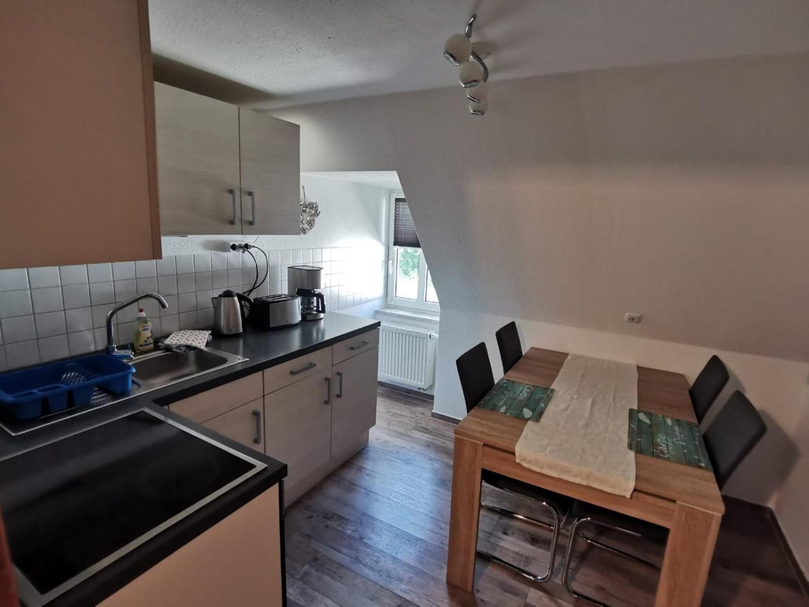 A compact kitchen with a dining area, featuring a sink, stove, and a dining table with chairs.