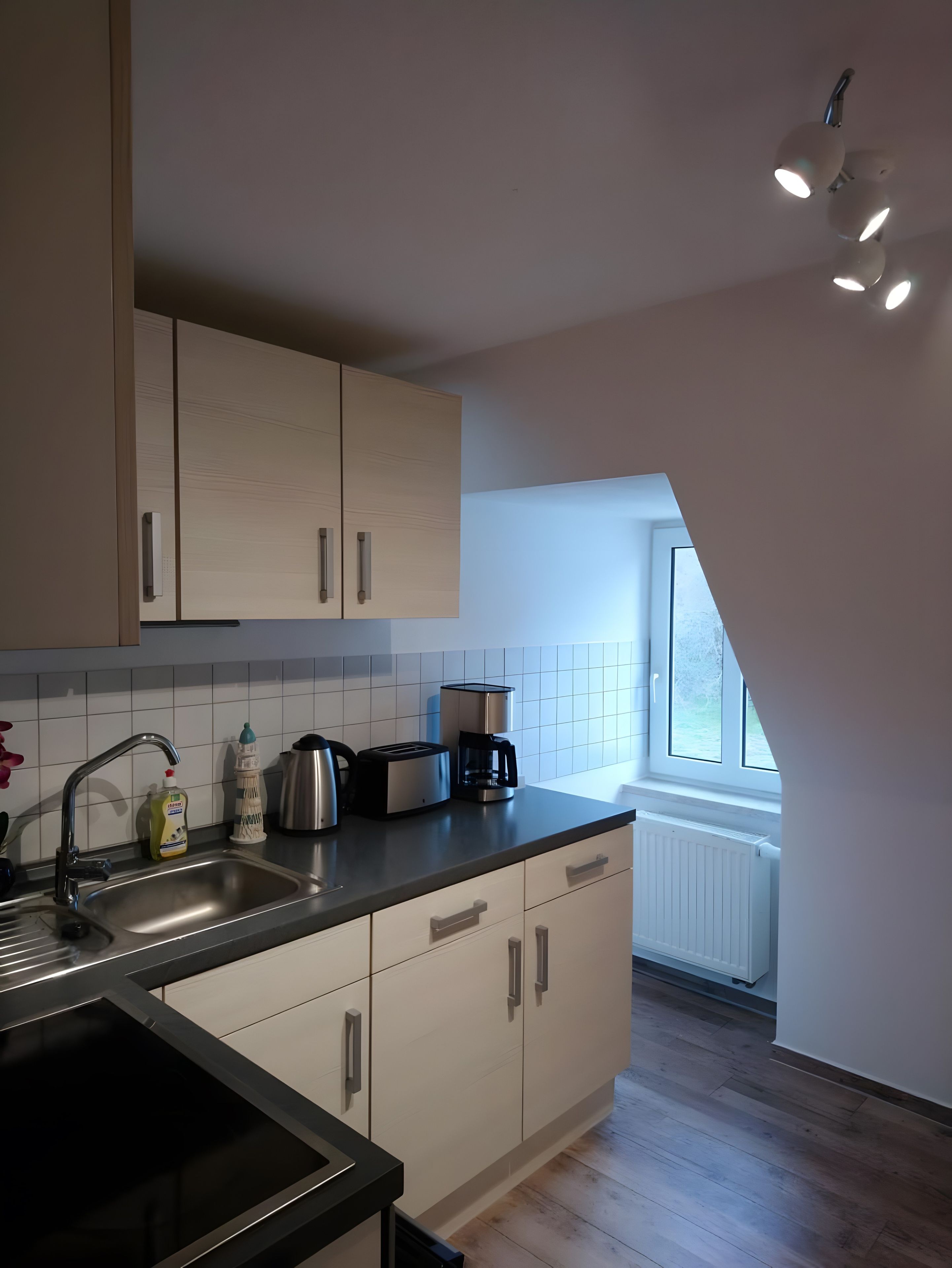 Eine moderne Küche mit Backofen, einer Kaffeemaschine und einem Fenster für natürliches Licht.