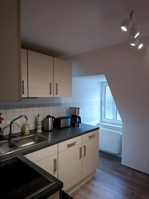 A modern kitchen with a built-in oven, a coffee maker, and a window providing natural light.