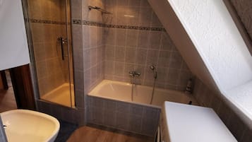A bathroom with a shower, bathtub, and sink.